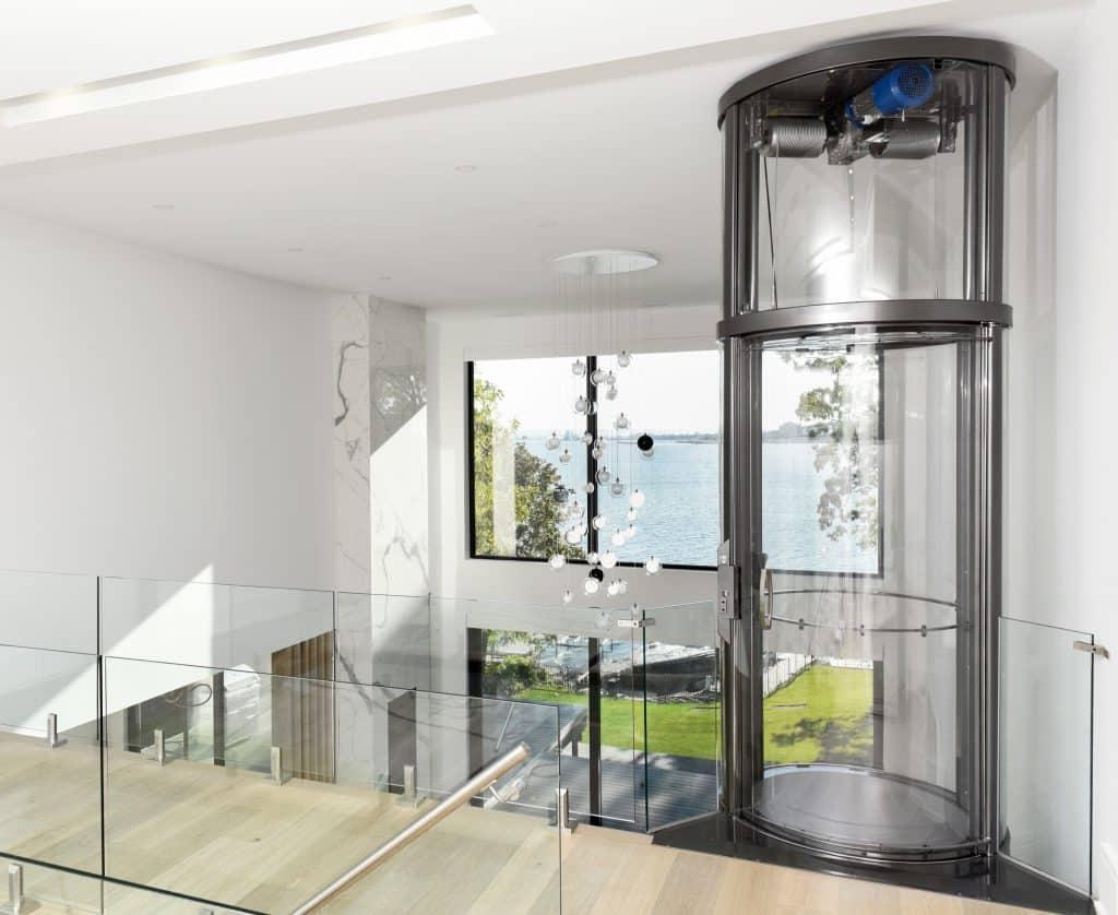 Circular glass elevator opening onto second story landing